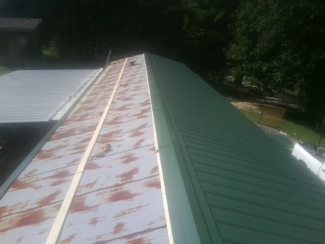 Old rusted panels beside newly installed green metal roofing — Wind Damage Roof Repair by Roofing Brothers in Viola