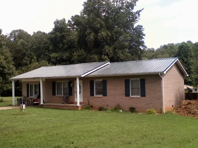 Gray metal roof on a brick ranch house with a side carport in Viola