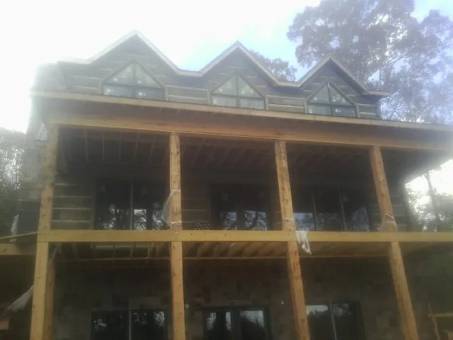 Dormers and porch framing on a large log home under construction — Roof Coating work by our crew in Viola